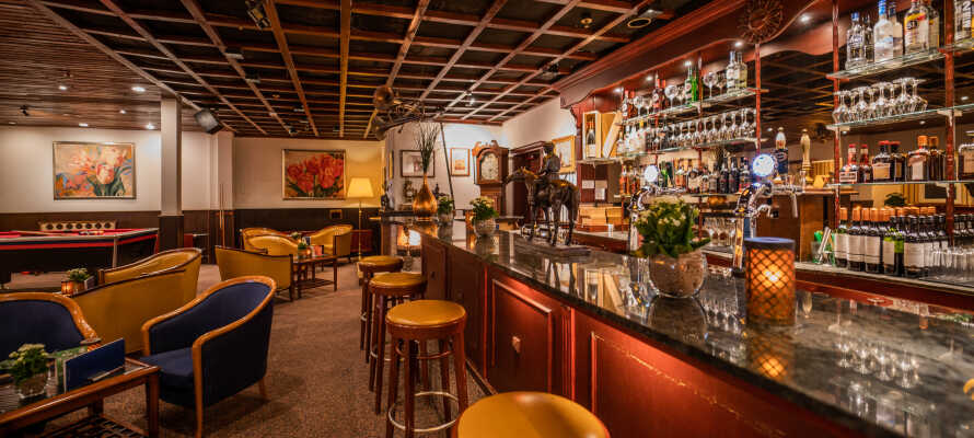 Den charmerende bar med pejs tilbyder en afslappende atmosfære for en kop kaffe, en drink eller et let måltid.